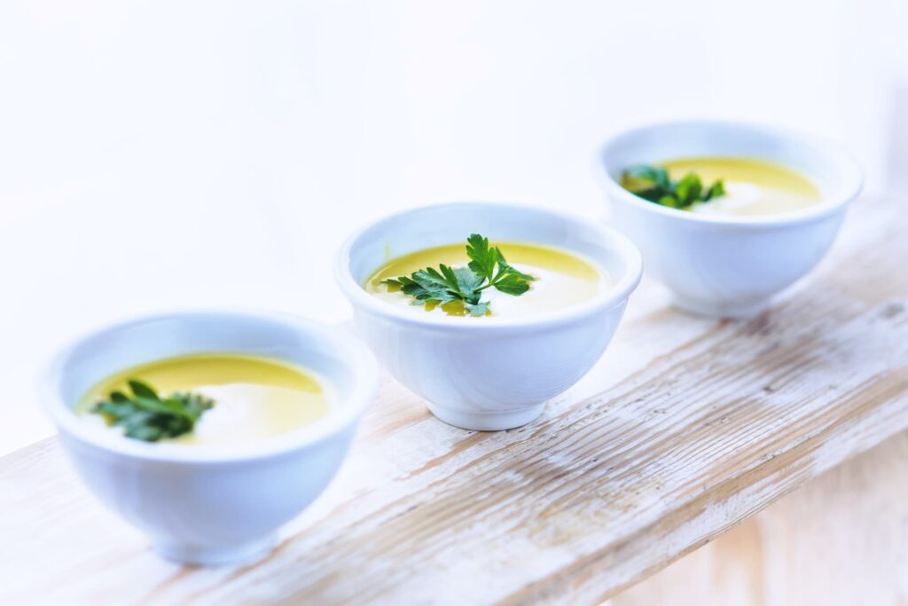 Three soup bowls with leek soup on a wooden surface.