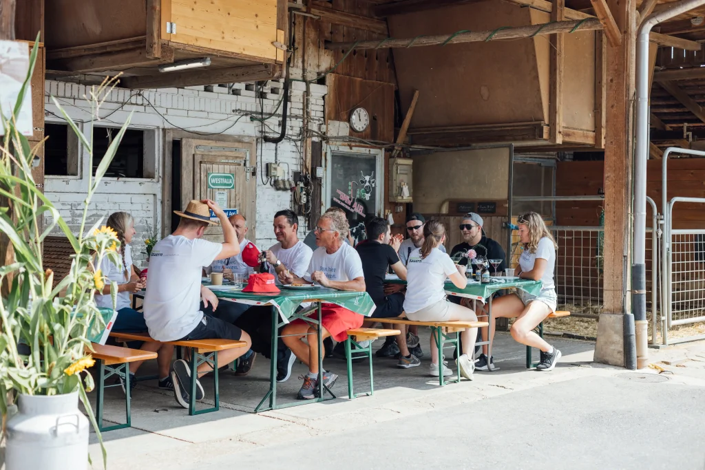Guests sit at beer-table benches in front of the barn.