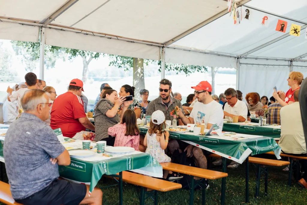 Guests sit at beer-table benches under a tent roof and enjoy the brunch.